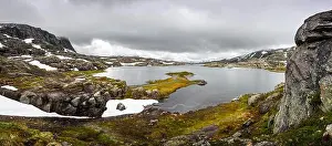 Typical norwegian landscape with snowy mountains and clear lake near the Trolltunga rock - most spectacular and famous scenic cliff in Norway