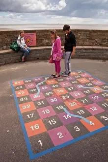 UK, England, Lincolnshire, Cleethorpes, seafront, children with mother playing game of giant snakes and ladders