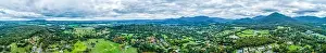 Ultra wide aerial panorama of scenic rural landscape with houses surrounded by trees, grasslands, and mountains