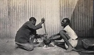 Zimbabwe Prints: Umtali, Zimbabwe: two African boys stirring a cooking pot. Photograph by J. Lomas, 1905
