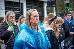 Walks Prints: Unhappy lady in disposable poncho joins a procession in Warrington Town Centre for St Patrick's Day