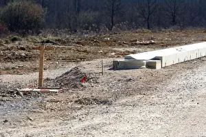 Road Construction Prints: Unpaved road features a wooden survey marker embedded in concrete