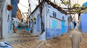 Chaouen Prints: Unrecognizable man on his back with typical Moroccan attire walking through the alleys of Chefchaouen