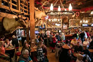 Illuminate Prints: USA, Alaska, Juneau, individuals gather and dine inside of the Red Dog Saloon in downtown Juneau