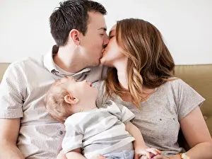 Young Couple Prints: USA, Utah, Salt Lake City, Young couple kissing with baby boy (6-11 months) on their lap