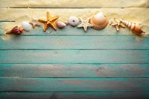 Vacations and summer time concept with starfish and sea shells on a turquoise wooden table with sand