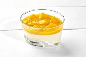 Vanilla panna cotta with mango puree and fresh fruits in glass