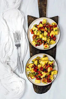 Potatoes Prints: Vegan potato salad with roasted bell peppers served on two plates photographed on a wooden cutting board on a white