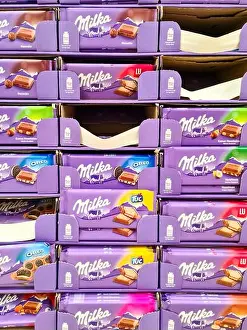 Kiel Prints: A vertical closeup of a large display with chocolate bars of different varieties of the Milka brand