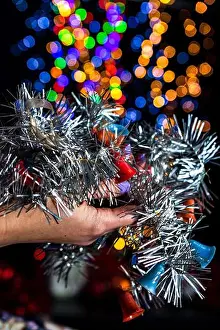 Garland Prints: A vertical closeup shot of holding a silver Christmas garland decoration isolated on bokeh background