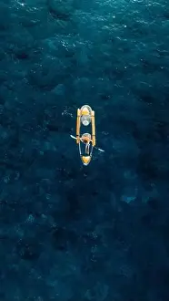 Blue Boat Prints: Vertical Screen: Woman on transparent kayak in tropical blue ocean. Drone view