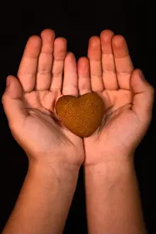 Heart Shaped Prints: Vertical shot of a child's hands holding a heart-shaped cookie - human kindness concept