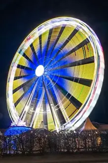Ferris Prints: A vertical shot of a Ferris wheel with bright blurry neon lights shining from it at night
