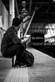 Train Transportation Prints: A vertical shot of a man waiting for his train in black and white