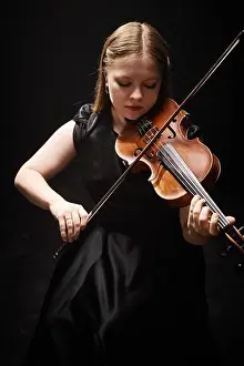Concentrate Prints: Vertical shot of professional female violinist in elegant black dress playing classical music in dark studio with top