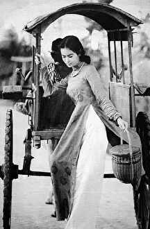 Outfit Prints: Vietnam: Young woman in an ao dai dress descending from a covered pony cart