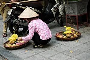 Baskets Prints: Vietnamese woman with typical conical hat selling pineapples in the old quarter of Hanoi