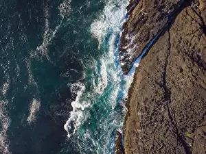 View from above. Bubbling turquoise ocean water and rocky shore