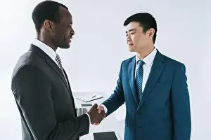 Coworkers Prints: side view of african american and asian businessmen shaking hands after meeting