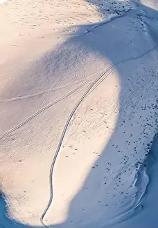 Top view of a beautiful mesmerizing view of the ski slope with ski trails located in the mountains on a sunny winter