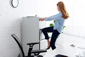Formal Wear Prints: Side view of businesswoman trying to opening cabinet driver near table in office