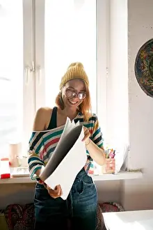Funky Prints: Side view of content female painter in funky outfit standing with art supplies in studio