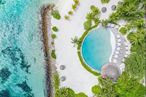 Top view from drone at beach, azure sea and poolside with palm tree in Maldives luxury resort. Tropical island, exotic aerial landscape