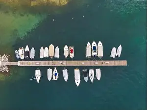 A top view of fishing boats anchoring in marina next to jetty wooden pier