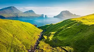 View from flying drone. Colorful summer scene of Faroe Islands and Tindholmur cliffs on background