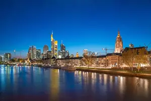 View of Frankfurt am Main skyline at dusk along Main river with cruise ship in Frankfurt, Germany