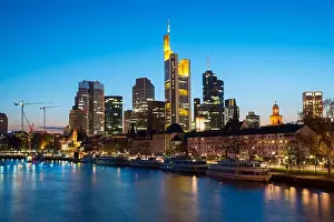 View of Frankfurt am Main skyline at dusk along Main river with cruise ship in Frankfurt, Germany