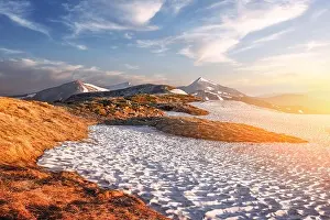 View of the grassy hills with orange tussocks and snowy mountains on background. Dramatic spring scene. Landscape photography