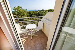 Stay Prints: View from hotel room balcony with white furniture overlooking Mediterranean greenery and sea