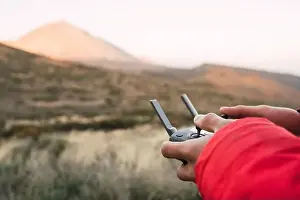 Remote Controller Prints: Side view of human holding joystick on land near top of mountain Teide in Tenerife