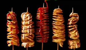 Mayo Prints: Top view layout of yummy crispy deep fried tornado potatoes on skewers with mayo and ketchup on black background