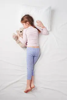 Napping Prints: Top view of little cute girl sleeping with teddy bear