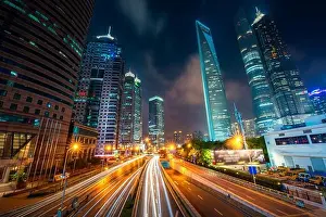 View of Lujiazui Business district skyscraper with traffic in street at night in Shanghai, China. Asian tourism, modern city life, or business finance