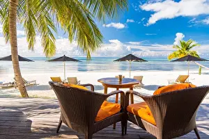 View of luxury beach scene with white fashion deckchairs on the beach.Umbrellas and blue sky with palm trees. Exotic travel destination banner concept