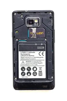 Back view of old smartphone with open cover isolated on white background. The battery and sim card are visible
