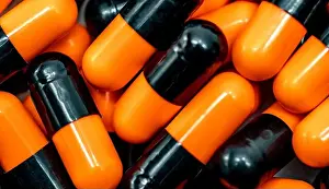 Pharmaceutics Prints: Top view of orange, black antibiotic capsule pills
