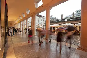 A view of people walking under the arches at Covent Garden during a rain shower