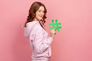 Recommendation Prints: Side view portrait of happy curly-haired teen female in hoodie showing hashtag sign