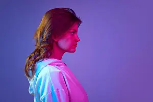 Hoodie Prints: Side view portrait of young pretty girl looking straight with serious facial expression against gradient blue purple