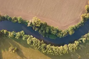 Land Day Prints: Top view of the river with turns of meanders and green forests in bright sunlight