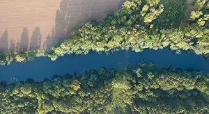Land Day Prints: Top view of the river with turns of meanders and green forests in bright sunlight