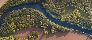 Land Day Prints: Top view of the river with turns of meanders and green forests in bright sunlight