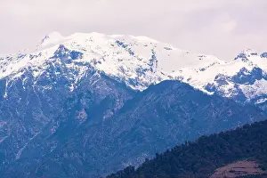 Bhutan Prints: A view of rugged mountains with snow on top from the road between Gangtey