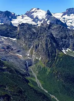 Upstream Prints: View of a small river with a waterfall flowing out of a mountain glacier