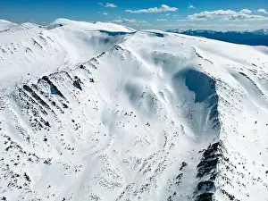 A top view of a snowy mountain range Kizly with a blue sky and clouds in the background. Carpathian mountain range