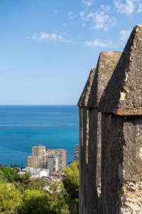 Historical Site Prints: A view from a stone wall overlooking a coastal city and the ocean